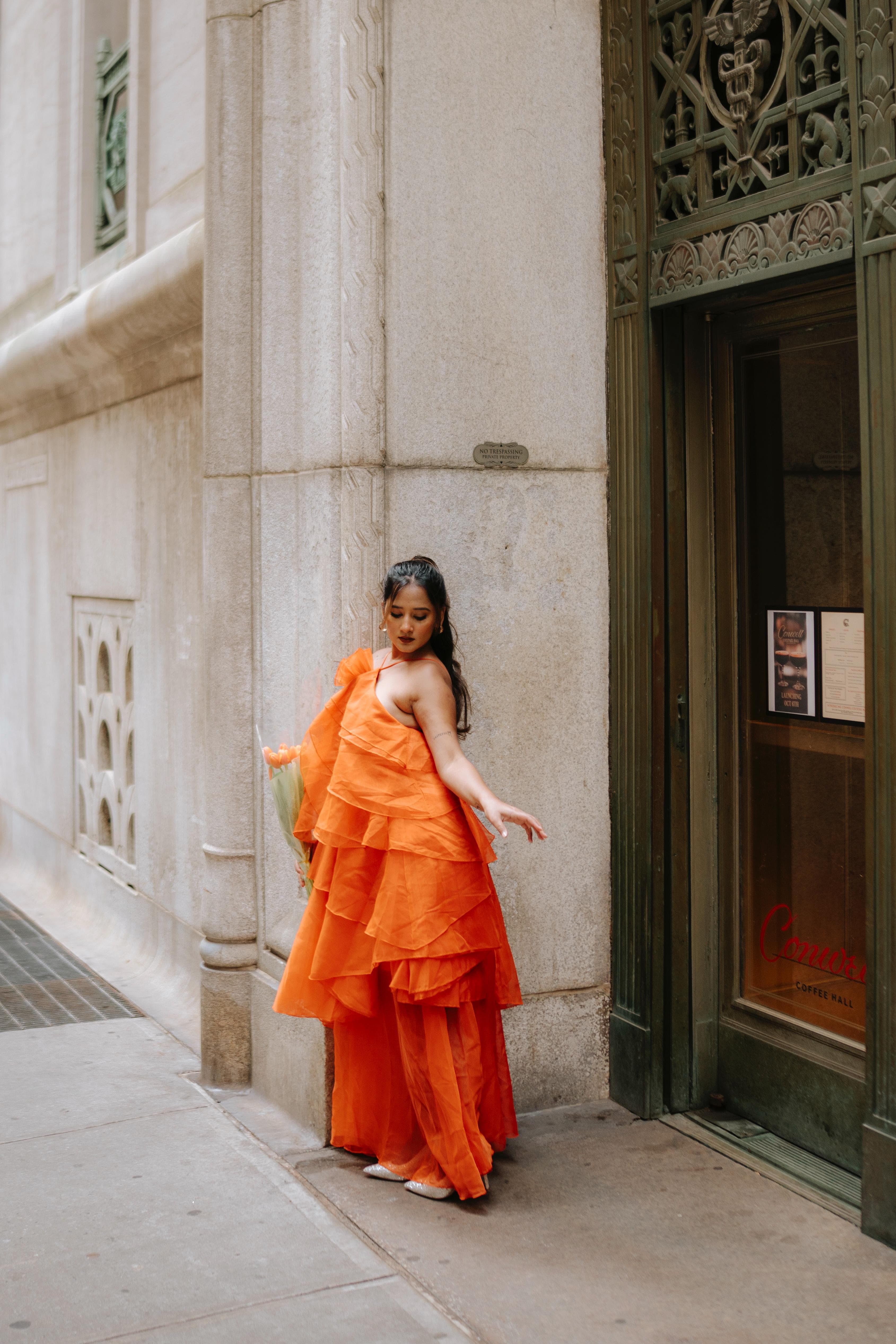 Maitreyi Tiwari wearing an orange statement gown on a city sidewalk